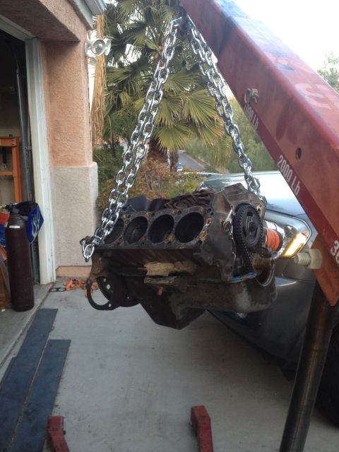 1992 Ford Bronco - Engine block is being lifted by a crane in front of a garage.