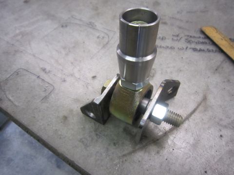2008 Jeep Wrangler - A metal joint part, possibly for a vehicle suspension or steering system, rests on a workbench next to some technical drawings.
