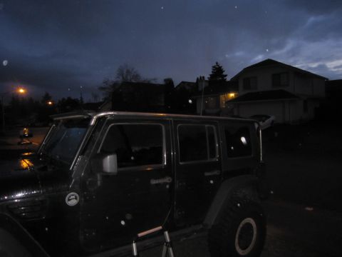 2008 Jeep Wrangler - The side profile of a black Jeep Wrangler is visible against a dark, cloudy sky.