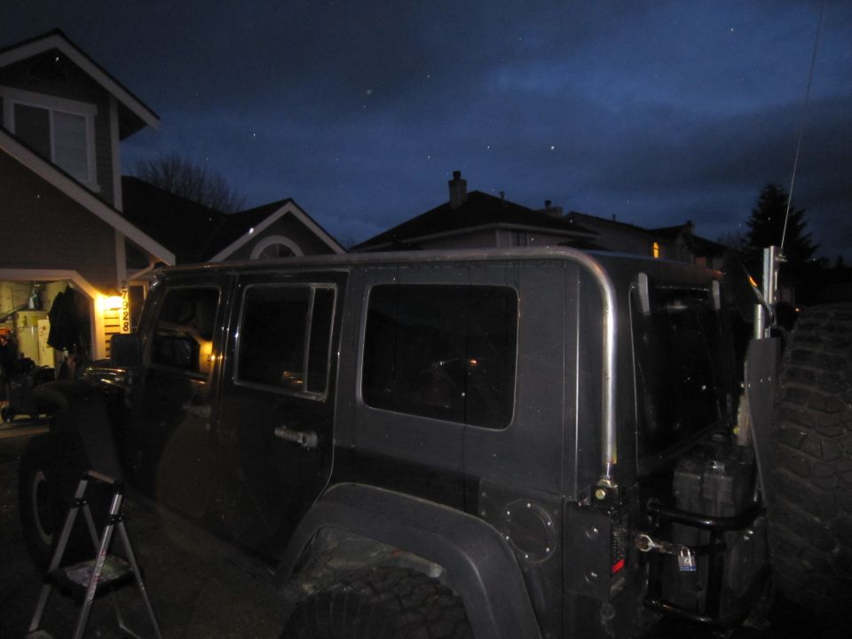 Side view of dark SUV with roof rack and spare tire carrier