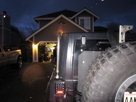2008 Jeep Wrangler - Rear view of a Jeep Wrangler with a spare tire and roof rack, parked in a driveway at night.
