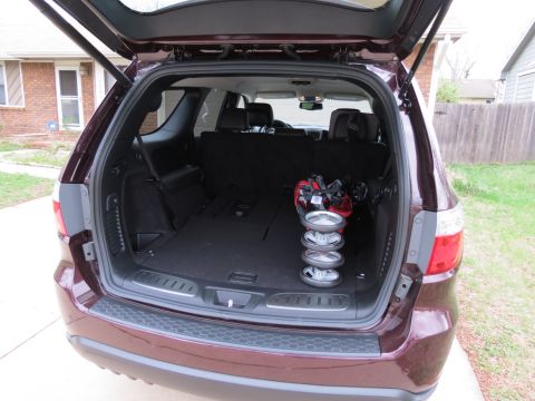 2012 Dodge Durango - The rear view of a maroon SUV shows its cargo area with golf equipment and stroller wheels.