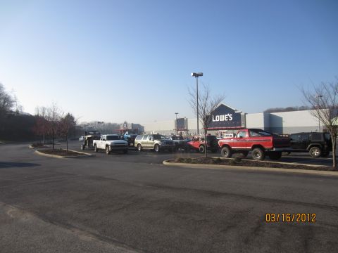 1979 Ford Bronco - Parking lot scene with multiple trucks and SUVs, including a red 1979 Ford Bronco, in front of a Lowe's store.