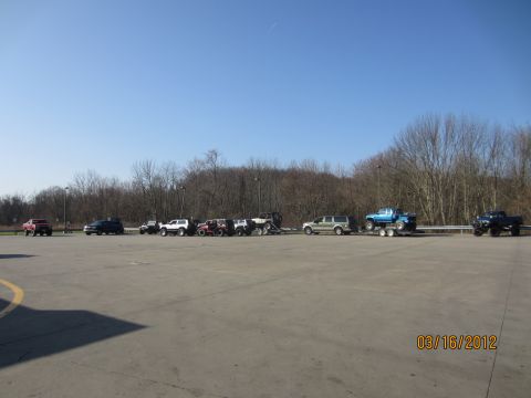 1979 Ford Bronco - A collection of trucks and off-road vehicles are parked in a lot on a sunny day.