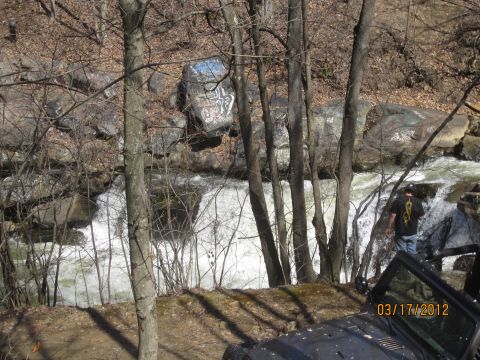 1979 Ford Bronco - A vehicle is parked on a dirt path overlooking a waterfall, with graffiti visible on rocks in the background.