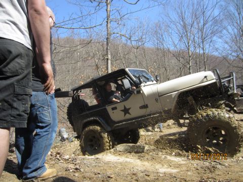 1979 Ford Bronco - Off-road Jeep Wrangler navigating a challenging muddy trail with spectators.