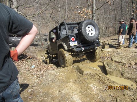 1979 Ford Bronco - A Jeep Wrangler tackles a challenging off-road course with onlookers observing the action.