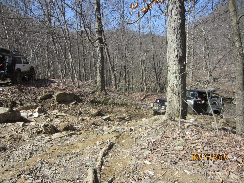 Off-road vehicles navigating a rocky, wooded trail