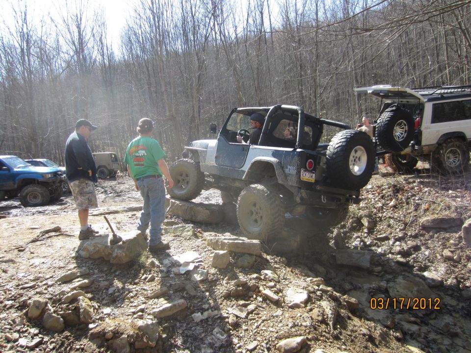 Jeep Wrangler navigating rocky terrain, rear-mounted spare tire visible