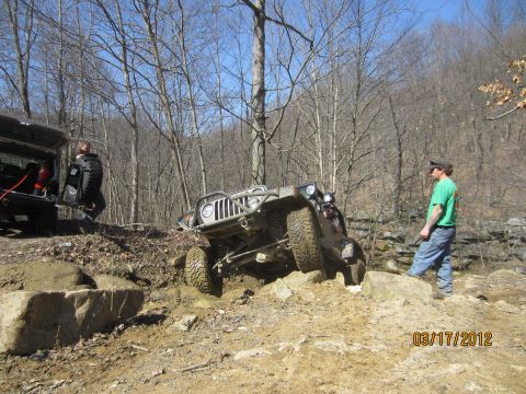1979 Ford Bronco - Off-road vehicles navigate challenging rocky terrain in a wooded area.