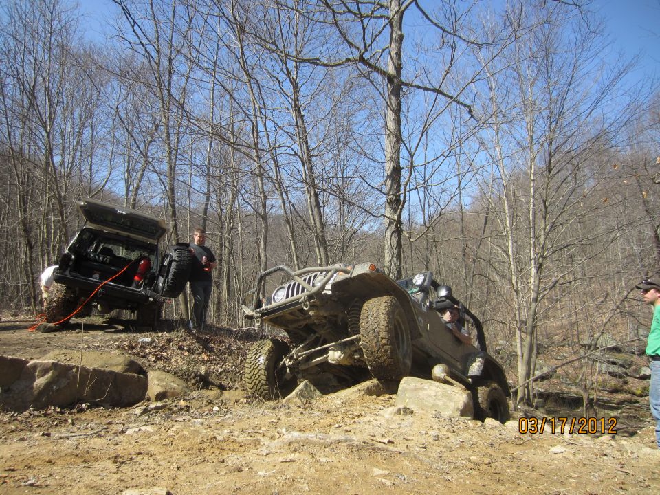 Two off-road vehicles navigating a rocky terrain, one with its rear door open