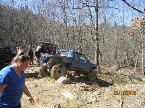 1979 Ford Bronco - Off-road enthusiasts tackle a challenging trail with multiple modified trucks in a wooded area.