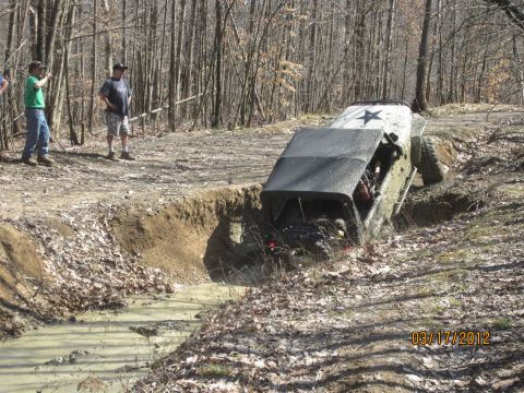 1979 Ford Bronco - This vehicle is attempting to cross a muddy obstacle with spectators observing the action.