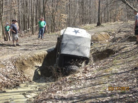 1979 Ford Bronco - An off-road vehicle navigates a challenging muddy terrain, getting stuck in a deep ditch.