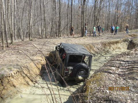 1979 Ford Bronco - Off-road vehicle navigates a challenging muddy terrain with onlookers present.