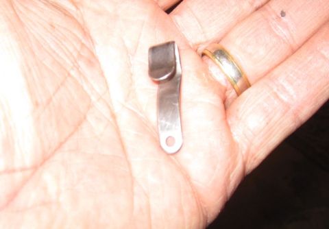 1990 Ford Bronco - A small metal clip is held in a hand, showing its shape and a small hole for attachment.