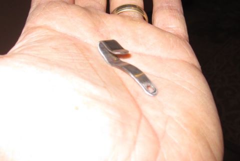 1990 Ford Bronco - A small, curved metal clip with a hole at one end rests in a person's hand.