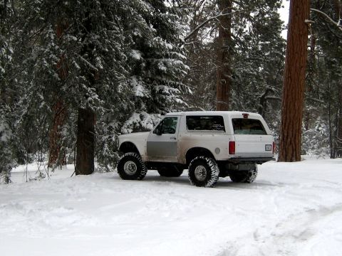 1996 Ford Bronco - This lifted SUV, likely a 1992 model, is parked in a snow-covered forest with pine trees all around.