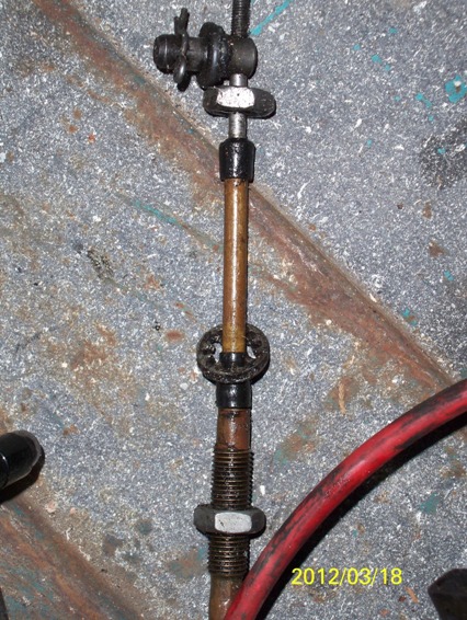 1968 Ford Ranchero - Detail of a mechanical linkage assembly, possibly from a vehicle's control system, with a red cable visible.