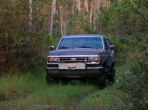 1991 Ford Bronco - 1991 Ford Bronco sits off-road in a forest clearing.
