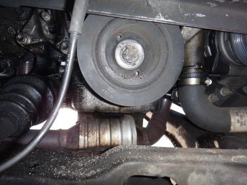 1993 Ford Taurus - Close-up view of engine parts, including a pulley and hoses, with debris scattered on the vehicle frame.