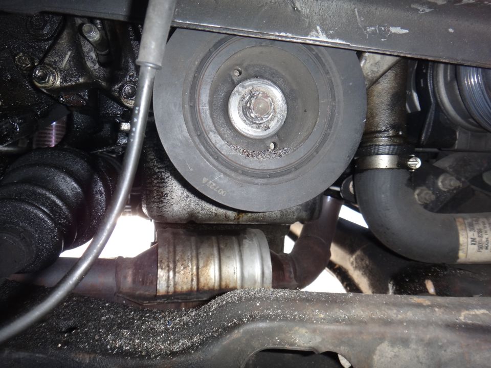 Engine pulley, hoses, and exhaust components with metal shavings on frame