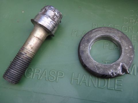 1993 Ford Taurus - A damaged bolt and washer lie on a green surface with embossed text.