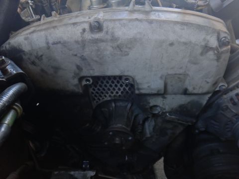 1993 Ford Taurus - Close-up view of engine parts, including a large metal cover and a black hose.