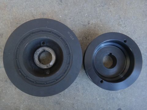 1993 Ford Taurus - Two crankshaft pulleys are shown side-by-side on a concrete surface. One pulley is larger and has a visible part number.