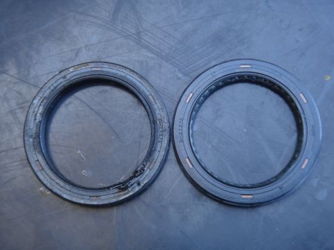 1993 Ford Taurus - Two oil seals, one used and one new, are shown side-by-side on a textured surface.
