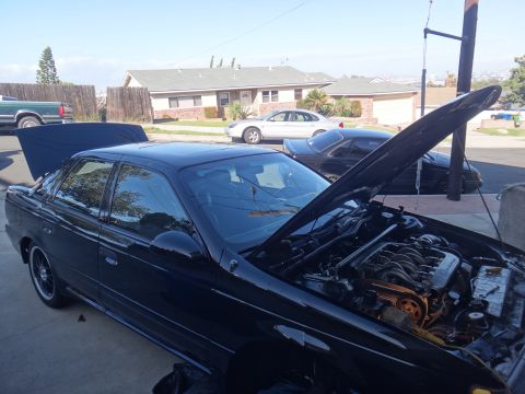 1993 Ford Taurus - A black sedan with its hood open, revealing the engine compartment, parked in a driveway.
