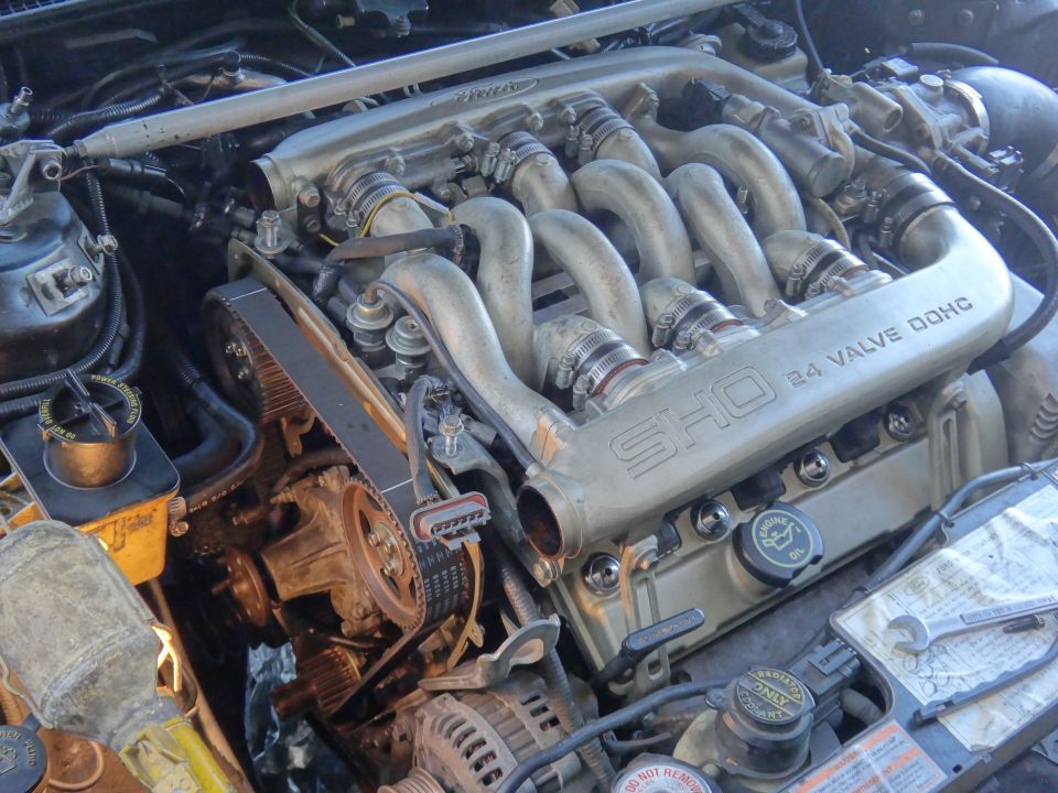 Engine bay with V6 engine, timing belt, and intake manifold visible. 'SHO 3.0L 24 VALVE DOHC' text on manifold