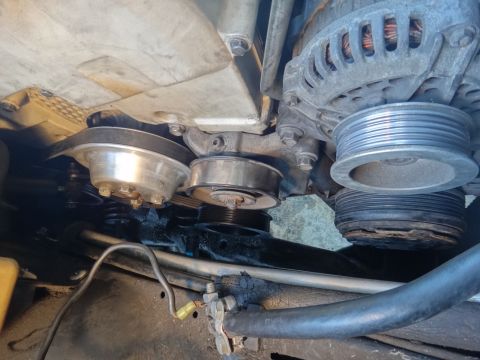 1993 Ford Taurus - Close-up view of engine components, including pulleys and alternator, under a vehicle.