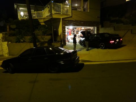 1993 Ford Taurus - Two dark sedans are parked in a driveway at night, with one vehicle's hood open.