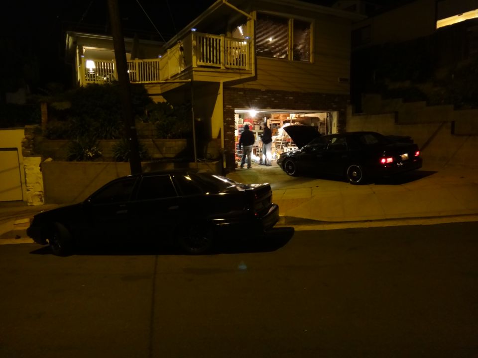Black sedan parked on street at night, side view