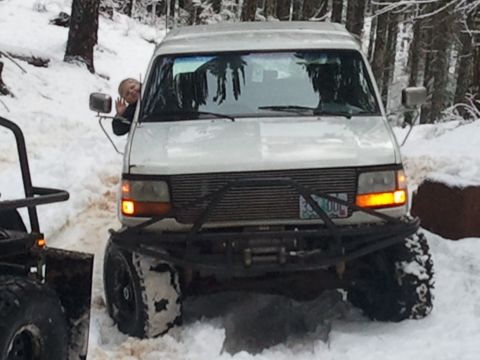 1994 Ford Bronco - A person waves from the window of a white van equipped with a heavy-duty bumper and winch, navigating a snowy terrain.