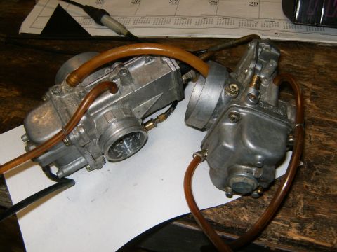 2000 Ford E350 - Close-up of two motorcycle carburetors, one marked 'JAPAN', resting on a surface with a calendar in the background.