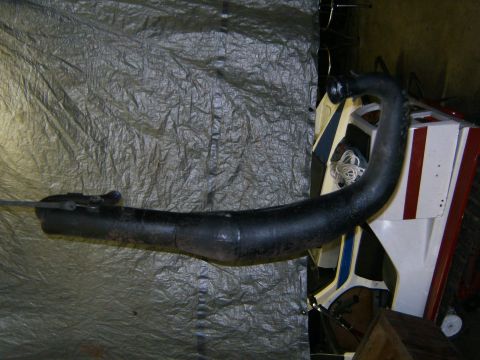 2000 Ford E350 - An exhaust pipe lies on a tarp, with a portion of a vehicle visible in the background.