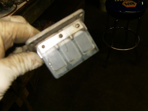 2000 Ford E350 - Close-up of a reed valve assembly, likely for an engine, held by a gloved hand.