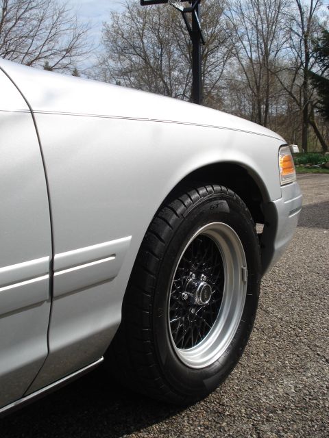 2000 Ford Crown Victoria - Front fender and wheel of a silver 2000 Ford Crown Victoria with aftermarket wire wheels.
