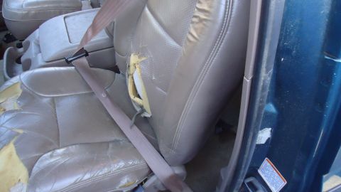 1996 Ford Bronco - Torn leather car seat interior with exposed foam and a seatbelt visible.