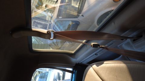 1996 Ford Bronco - Interior view of a vehicle, showing a seatbelt and sunroof. Another vehicle is visible outside.