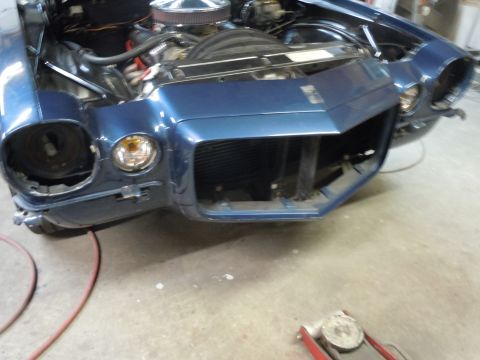 1973 Chevrolet Camaro - Front view of a blue 1970 Chevrolet Camaro undergoing repairs, showing the engine and missing headlight assembly.