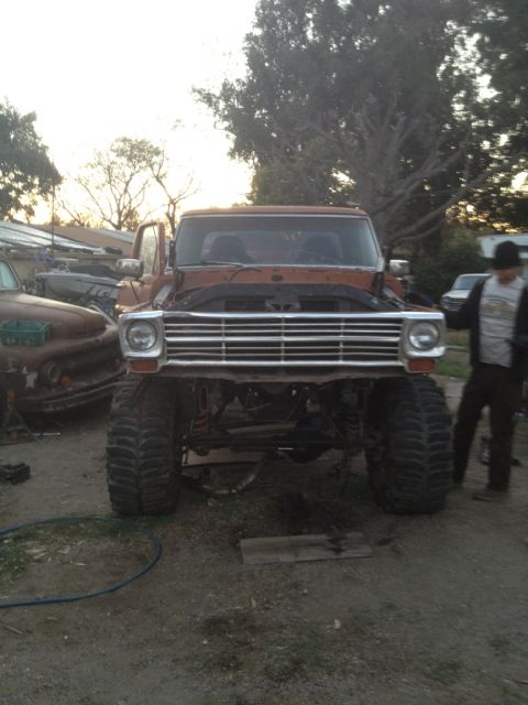 1969 Ford F-250 - Front view of a 1969 Ford F-250 pickup truck with its hood open and oversized tires, parked outdoors.