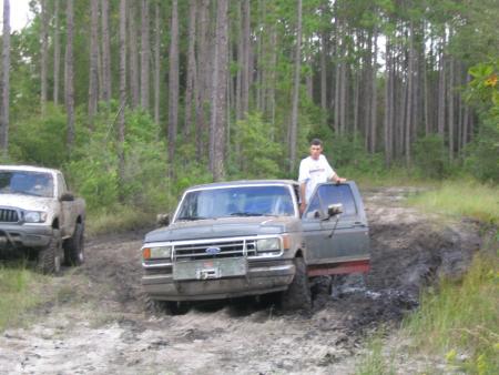 1991 Ford Bronco - A 1991 Ford Bronco is stuck in the mud while another truck is visible to the left.