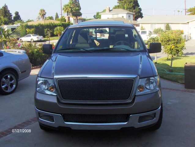 Front view of gray Ford F-150 pickup with billet grille parked in driveway