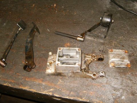 2000 Ford E350 - Disassembled brake master cylinder components and linkage parts laid out on a workbench surface.