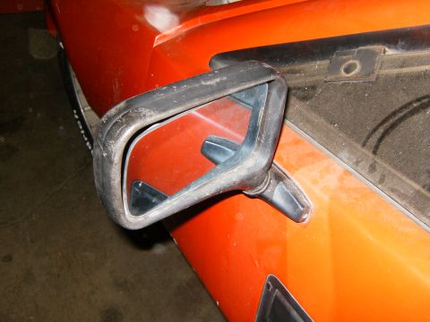 2000 Ford E350 - The side mirror assembly is attached to the orange body panel of the vehicle.