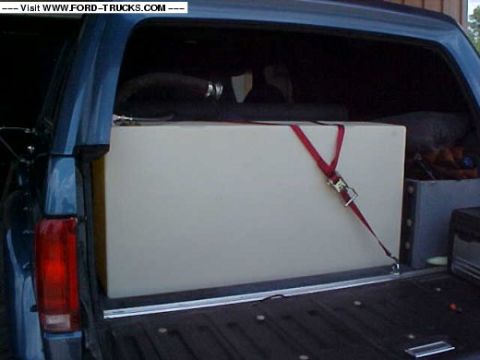 1992 Ford Bronco - The cargo area of a 1992 Ford Bronco holds a large white tank, secured by red straps.