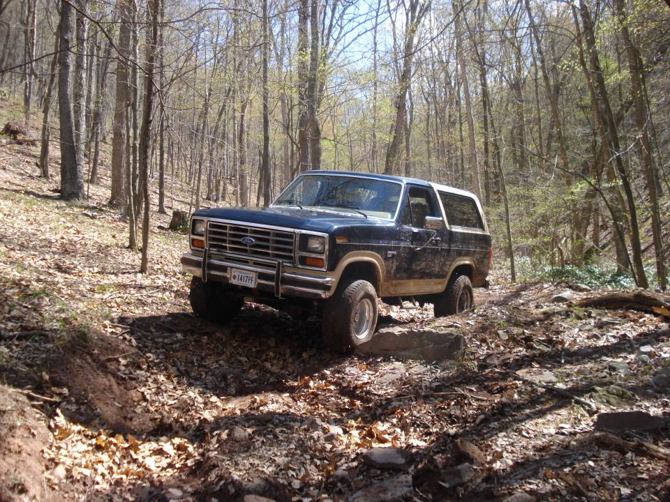 1985 Ford Bronco navigating a rocky forest trail